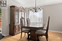 Elegant dining room showcasing hardwood flooring, a dark wood pedestal dining table with seating for four, and upholstered chairs with tall backs - 