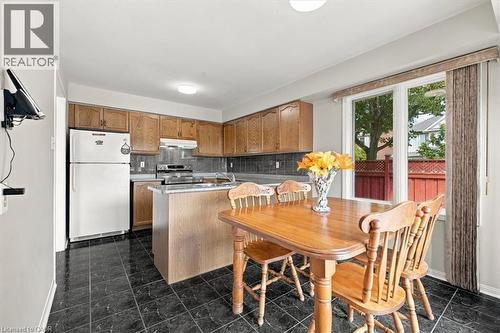Bright kitchen and dining area featuring wood cabinetry, stainless steel appliances, and a center island with wood-finish countertop - 5180 Oakley Drive, Burlington, ON 