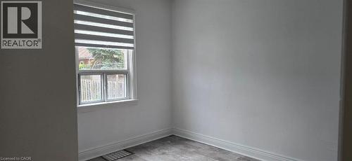Bright interior space featuring a window with integrated blinds, wood-finish flooring, and white painted walls - 284 Brucedale Avenue E, Hamilton, ON 