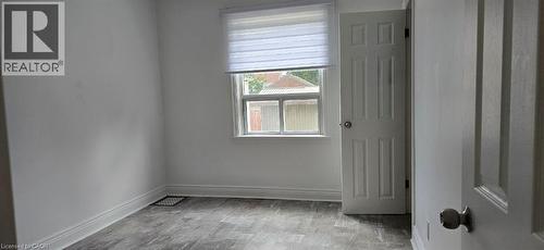 Wood-finish flooring, white paneled door, and a single window with blinds - 284 Brucedale Avenue E, Hamilton, ON 