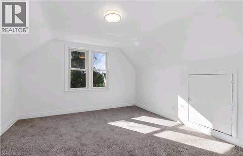White painted walls, sloped ceiling, gray carpet, double-hung windows, and a flush-mounted ceiling light fixture - 284 Brucedale Avenue E, Hamilton, ON 
