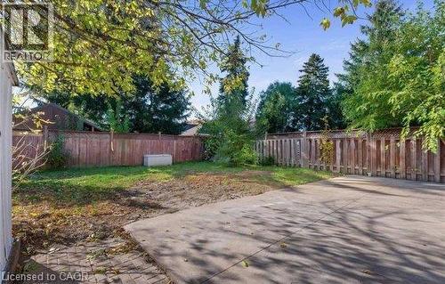 Expansive backyard featuring a concrete patio, brick paver section, wood privacy fencing, and mature trees - 284 Brucedale Avenue E, Hamilton, ON 
