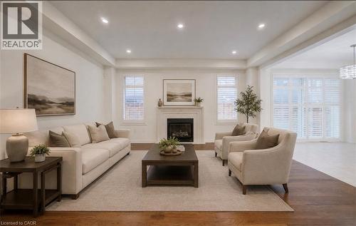 Recessed lighting illuminating the high ceilings, a fireplace with a mantel, dark wood-finish flooring, and white window shutters - 52 Pointer Street, Cambridge, ON 