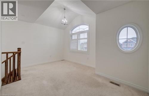 Vaulted ceiling with chandelier, arched window with plantation shutters, oval window, and carpeting - 52 Pointer Street, Cambridge, ON 