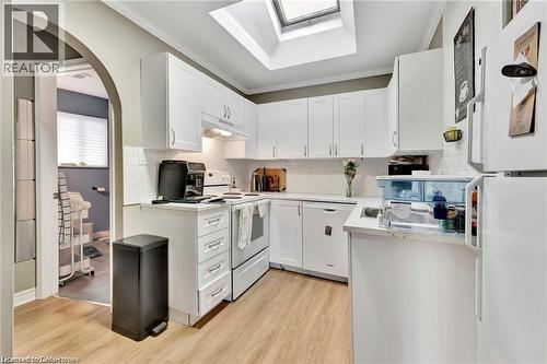 Kitchen featuring white cabinetry, white subway tile backsplash, light wood-finish flooring, and an overhead skylight - 93 Robertson Crescent, Kitchener, ON 