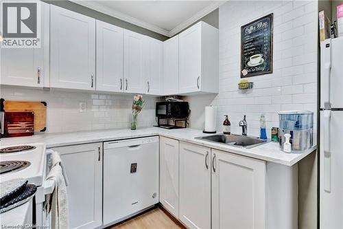 White shaker cabinetry, subway tile backsplash, stainless steel sink, and wood-finish flooring - 93 Robertson Crescent, Kitchener, ON 