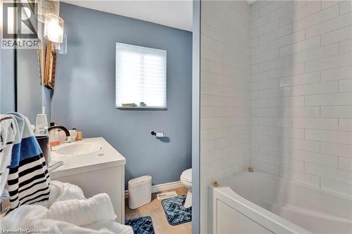 White subway tile shower surround with a built-in bathtub, a single vanity with an integrated sink, and a window with blinds - 93 Robertson Crescent, Kitchener, ON 