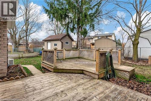 Expansive backyard featuring a multi-level wood deck with lattice railing, a detached storage shed, a manicured lawn, and mature trees - 93 Robertson Crescent, Kitchener, ON 