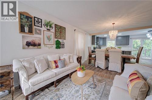 Open-concept living and dining area with wood-finish flooring, recessed lighting, and a crystal chandelier - 317 Christopher Drive, Cambridge, ON 