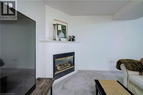 Corner fireplace with a white mantel and trim, featuring a dark metal firebox - 317 Christopher Drive, Cambridge, ON 