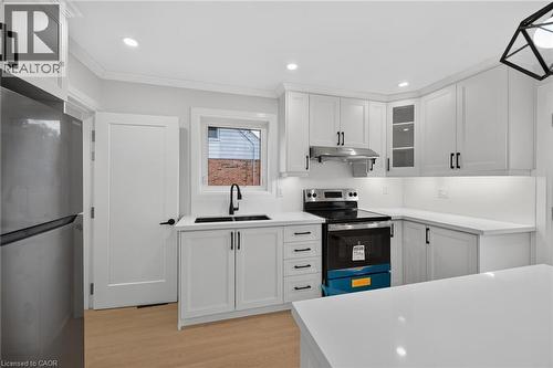 Contemporary kitchen featuring white cabinetry, a stainless steel refrigerator, and a black range - 50 West 4Th Street, Hamilton, ON 