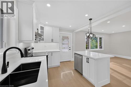 Bright kitchen featuring white cabinetry, a kitchen island with built-in dishwasher, and recessed lighting - 50 West 4Th Street, Hamilton, ON 