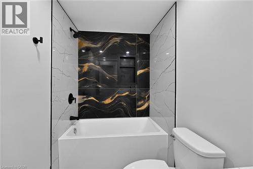 White soaking tub with black and gold patterned accent tile - 50 West 4Th Street, Hamilton, ON 