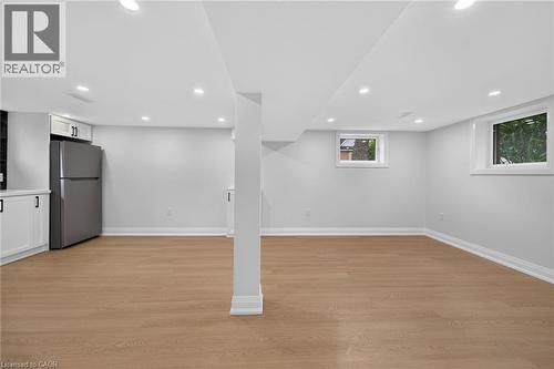Recessed ceiling lighting, wood-finish flooring, white cabinetry with dark hardware, and a stainless steel refrigerator - 50 West 4Th Street, Hamilton, ON 