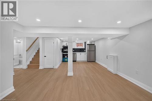 Open-concept lower level with wood-finish flooring, recessed lighting, and a full kitchen with stainless steel appliances - 50 West 4Th Street, Hamilton, ON 