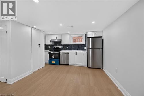 Recessed lighting illuminates the space, featuring wood-finish flooring and white walls - 50 West 4Th Street, Hamilton, ON 