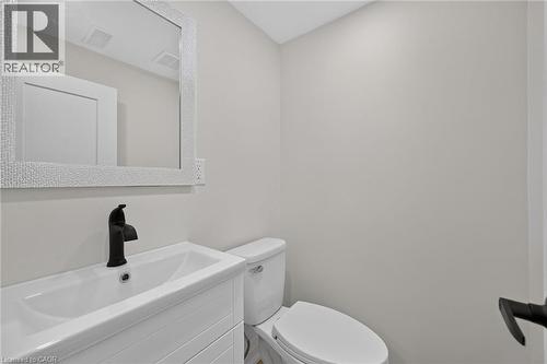 White vanity with a rectangular basin sink, matte black faucet, and a textured framed mirror - 50 West 4Th Street, Hamilton, ON 