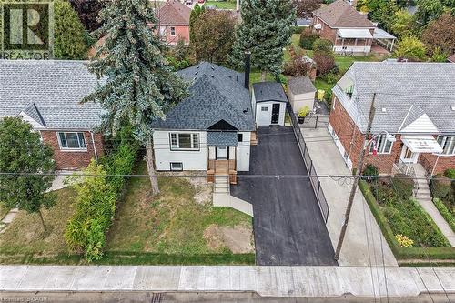 Front exterior featuring a dark asphalt driveway, white siding, and a dark shingle roof - 50 West 4Th Street, Hamilton, ON 