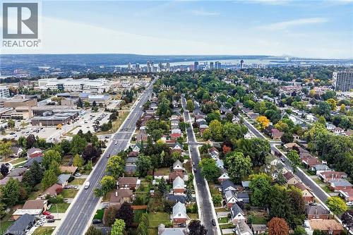 Aerial perspective showcasing suburban residences, mature trees, and urban infrastructure including commercial buildings and a distant city skyline - 50 West 4Th Street, Hamilton, ON 