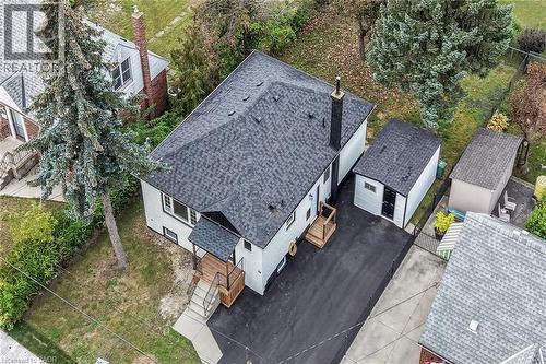 Modern renovation featuring a freshly paved driveway, updated asphalt shingle roofing, and a clean white exterior with contemporary siding - 50 West 4Th Street, Hamilton, ON 