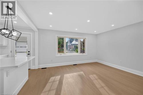 Recessed ceiling lighting, wood-finish flooring, white trim, a large window, and a modern pendant light fixture - 50 West 4Th Street, Hamilton, ON 