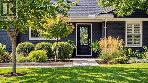Dark-toned exterior siding with white trim, a decorative front door with glass inlay, and a stone-paver walkway - 896 Eagle Drive, Burlington, ON 