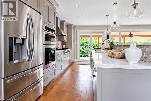 Stainless steel appliances, light gray cabinetry, wood-finish flooring, white countertop, and pendant lighting - 896 Eagle Drive, Burlington, ON 