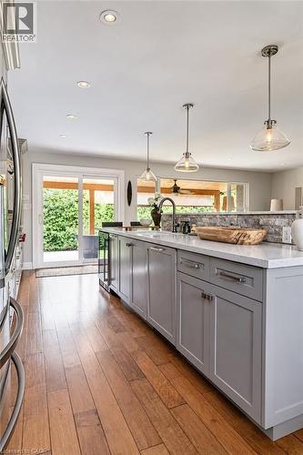 Kitchen island featuring grey cabinetry, white countertops, and integrated sink with a gooseneck faucet - 896 Eagle Drive, Burlington, ON 