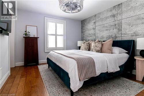 Hardwood flooring, window with white plantation shutters, ceiling-mounted light fixture, and a built-in architectural accent wall - 896 Eagle Drive, Burlington, ON 