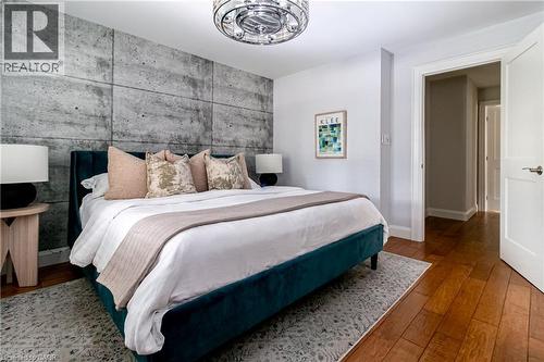 Accent wall with concrete-style paneling, hardwood-style flooring, and a contemporary ceiling fixture - 896 Eagle Drive, Burlington, ON 