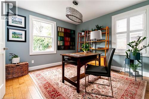 Hardwood flooring, two large windows, white window trim, white plantation shutters, and a decorative ceiling light fixture - 896 Eagle Drive, Burlington, ON 