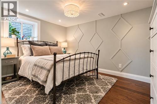 Decorative accent wall with geometric molding, recessed lighting, wood-finish flooring, and a window with a white frame - 896 Eagle Drive, Burlington, ON 