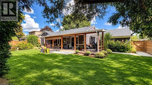 Expansive lawn area, covered patio with wood beam accents, multiple large windows, and a wood privacy fence - 896 Eagle Drive, Burlington, ON 