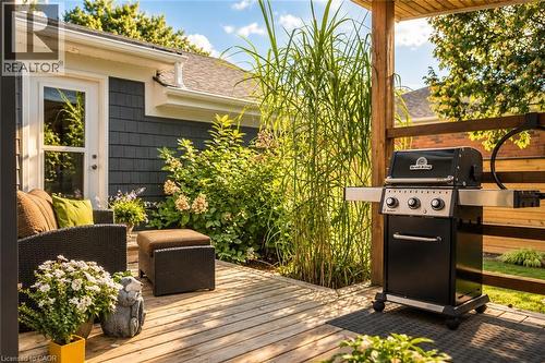 Covered wooden deck with a privacy fence, dark gray shingle siding, and a glass-paneled exterior door - 896 Eagle Drive, Burlington, ON 