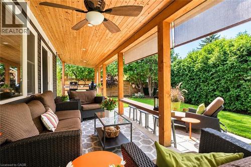 Covered outdoor patio featuring a wood plank ceiling with a ceiling fan, recessed lighting, and a stone paver patio - 896 Eagle Drive, Burlington, ON 
