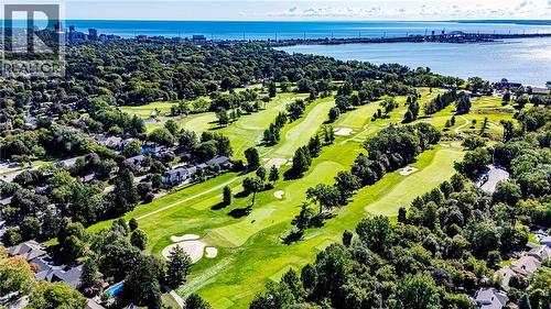 Expansive green golf course with sand traps, surrounded by lush mature trees, with a large body of water and distant cityscape visible - 896 Eagle Drive, Burlington, ON 