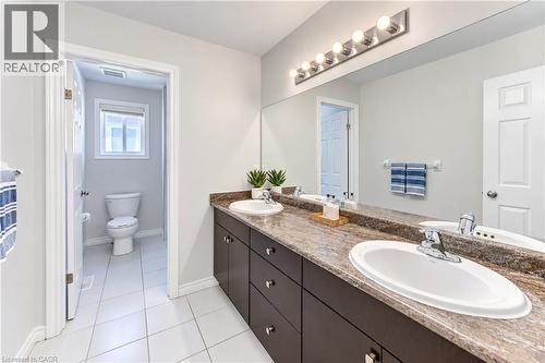 Double vanity with integrated sinks, a wide mirror, and a multi-bulb light fixture - 365 Woolwich Street, Waterloo, ON 