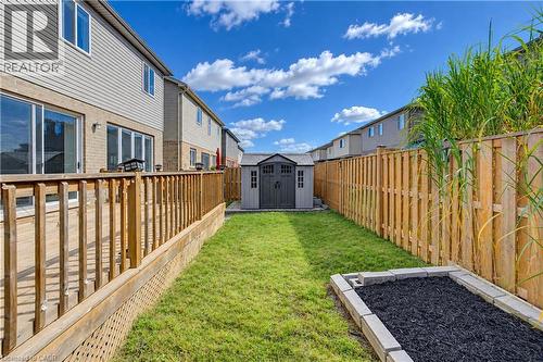 Expansive backyard featuring a wood deck, manicured lawn, built-in storage shed, and raised garden bed - 365 Woolwich Street, Waterloo, ON 