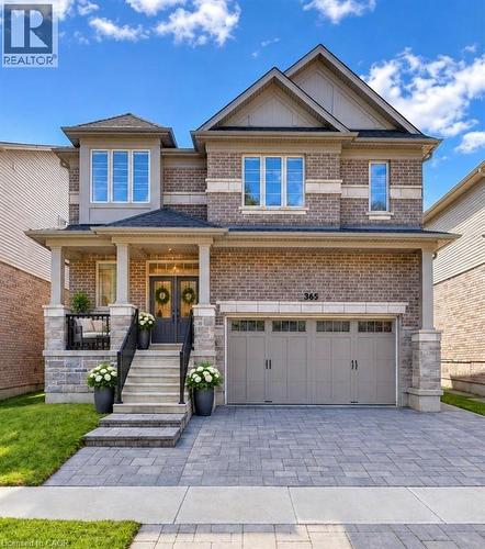 Brick and stone facade, double front doors, covered porch, paver driveway, and an attached two-car garage - 365 Woolwich Street, Waterloo, ON 