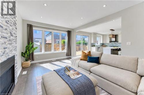 Open-concept living area featuring a stone accent wall, recessed lighting, wood-finish flooring, and expansive windows - 365 Woolwich Street, Waterloo, ON 