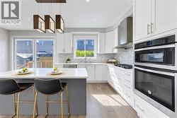 White shaker cabinetry, built-in stainless steel appliances, wood-finish flooring, white countertops, and a white tile backsplash - 