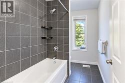 White bathtub with chrome fixtures, dark gray tile surround, and built-in shelving - 
