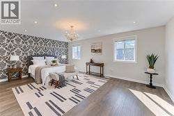 Recessed lighting, chandelier, two windows, wood-finish flooring, and a decorative accent wall - 