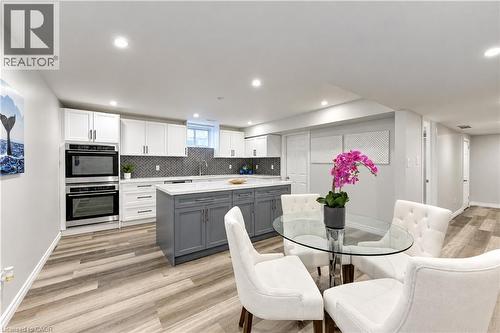 Kitchen featuring recessed lighting, wood-finish flooring, two-tone cabinetry, stainless steel built-in ovens, and a kitchen island with a light-colored countertop - 365 Woolwich Street, Waterloo, ON 