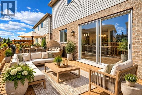 Expansive wooden deck featuring multiple defined zones, brick and siding exterior, and sliding glass doors - 365 Woolwich Street, Waterloo, ON 
