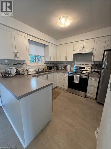 White cabinetry, light-toned countertops, tile backsplash, wood-finish flooring, and stainless steel appliances - 281 Toll Gate Boulevard, Waterloo, ON 