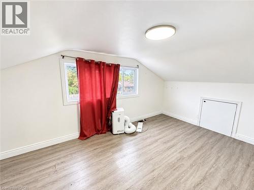 Sloped ceiling room featuring wood-finish flooring, a single window, and a built-in access panel - 84 Weber Street S, Waterloo, ON 
