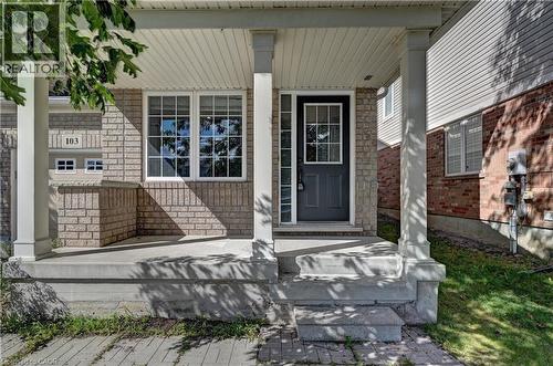 Brick and siding exterior featuring a covered porch, white-framed windows, and a panel-style entry door with divided lites - 103 Blackbird Circle, Cambridge, ON 
