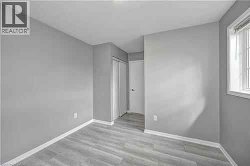 Light gray wood-finish flooring, neutral gray painted walls, white trim, and a white framed window with blinds - 103 Blackbird Circle, Cambridge, ON 