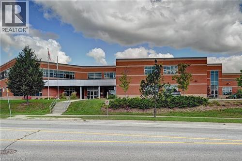 Brick exterior featuring multiple windows, a prominent entrance with steps, and a landscaped front area with mature trees - 103 Blackbird Circle, Cambridge, ON 